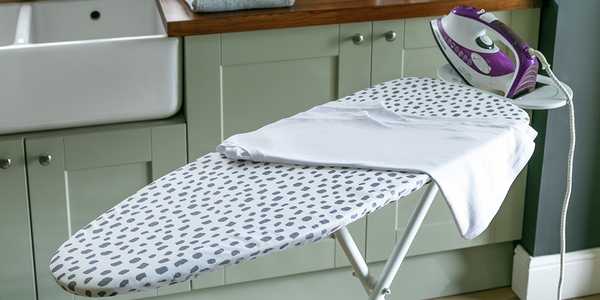 A Habitat ironing board with dalmation print placed in a utility room. 
